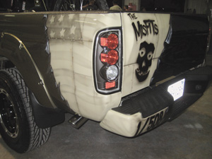 the torn-out look in the left rear of the truck, complete with clary’s unit’s misfits logo, ghosted american flag and company/battalion number.