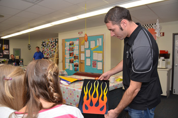 PPG painter Jason Lutton displays a flame-painted panel to Hudson Middle School students.
